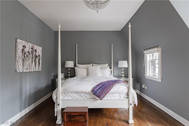 bedroom with baseboards, wood finished floors, and vaulted ceiling