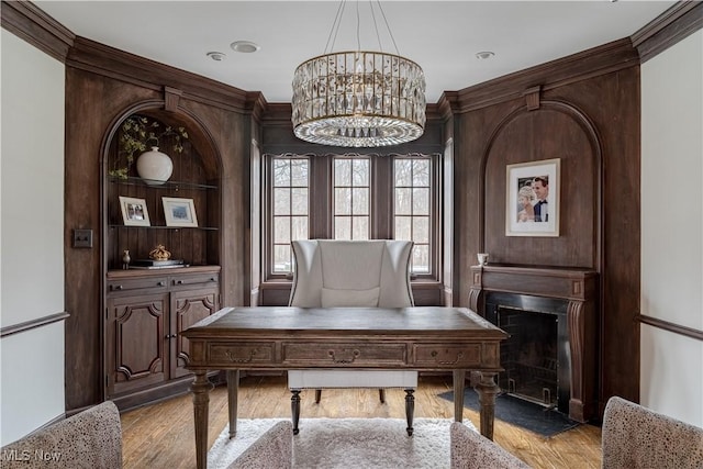 home office featuring a chandelier, a fireplace with flush hearth, and wood finished floors