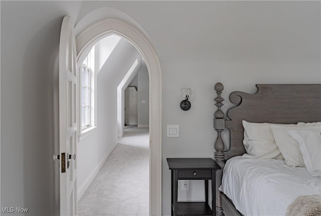 bedroom featuring arched walkways, baseboards, and carpet