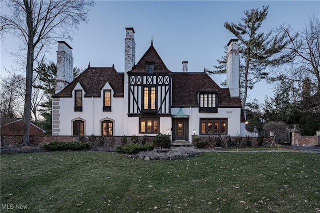 english style home featuring a front lawn and a chimney