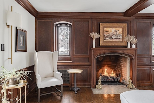 sitting room with dark wood finished floors, a fireplace with flush hearth, and ornamental molding