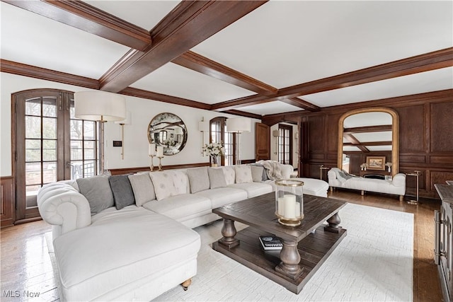 living room with beamed ceiling, coffered ceiling, wood-type flooring, crown molding, and a decorative wall