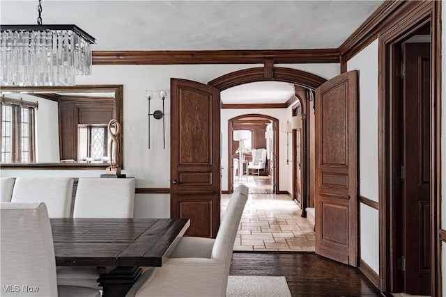 unfurnished dining area with baseboards, arched walkways, and ornamental molding