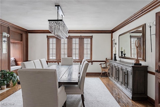 dining room featuring a chandelier, crown molding, baseboards, and wood finished floors