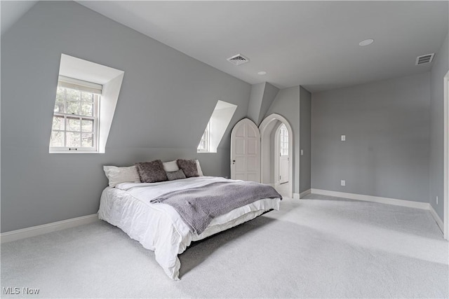 bedroom featuring visible vents, lofted ceiling, and carpet