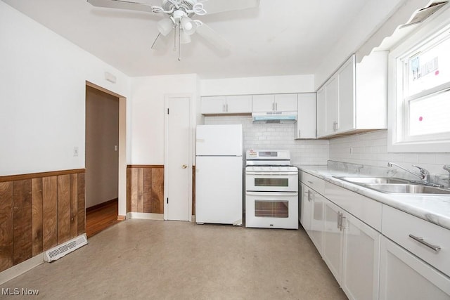 kitchen with visible vents, a wainscoted wall, under cabinet range hood, a sink, and white appliances