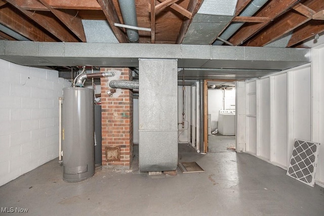 below grade area featuring heating unit, concrete block wall, washer / dryer, and water heater