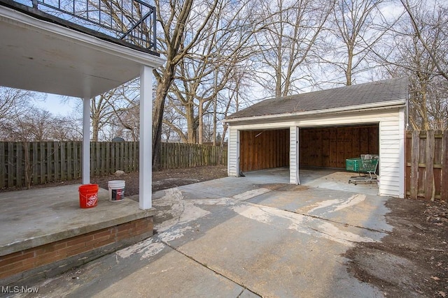 view of patio featuring an outbuilding, fence, and a garage