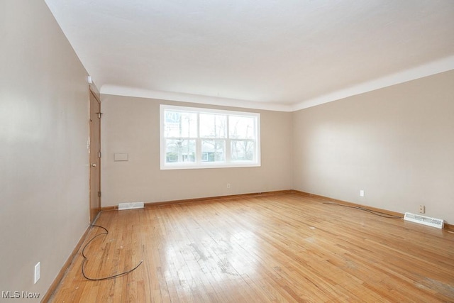 spare room featuring visible vents, light wood-style flooring, and baseboards