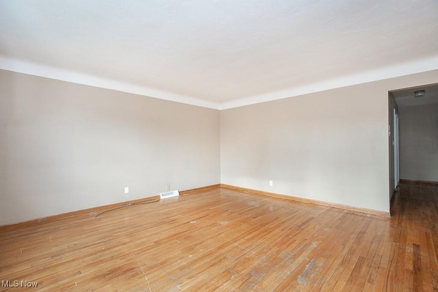 empty room featuring visible vents, baseboards, and light wood finished floors