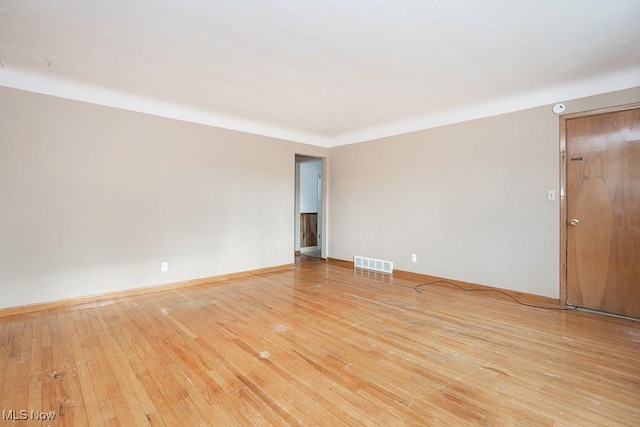 spare room featuring visible vents, light wood-style flooring, and baseboards