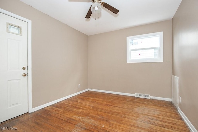 empty room with visible vents, ceiling fan, baseboards, and wood finished floors