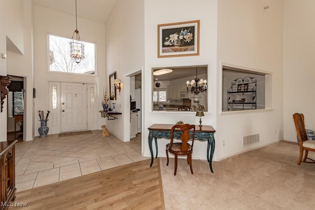 tiled entrance foyer featuring an inviting chandelier, a high ceiling, baseboards, and visible vents