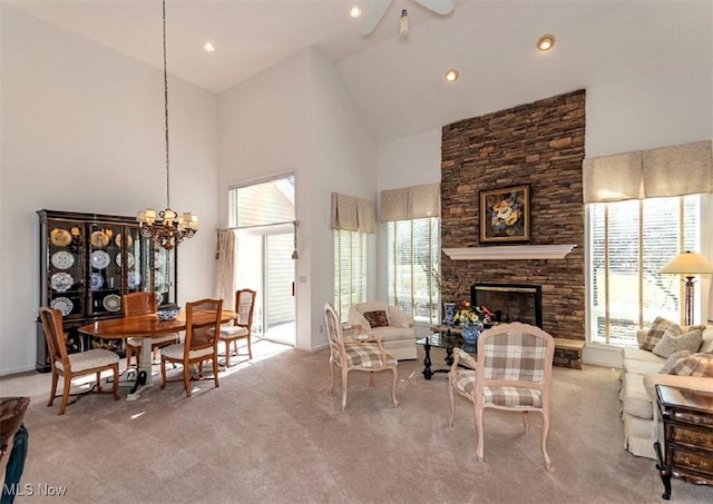 living area with a stone fireplace, a notable chandelier, carpet floors, and high vaulted ceiling