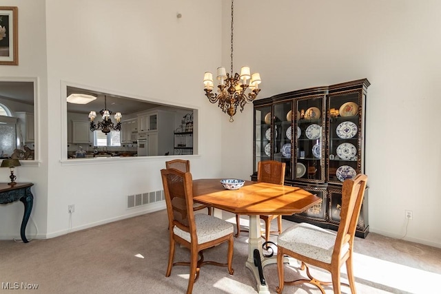 dining space with visible vents, baseboards, a chandelier, carpet floors, and a towering ceiling