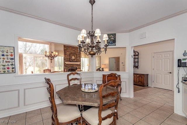 dining space featuring a decorative wall, a healthy amount of sunlight, a chandelier, and ornamental molding