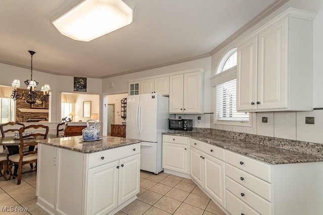 kitchen featuring a center island, freestanding refrigerator, white cabinets, crown molding, and a chandelier