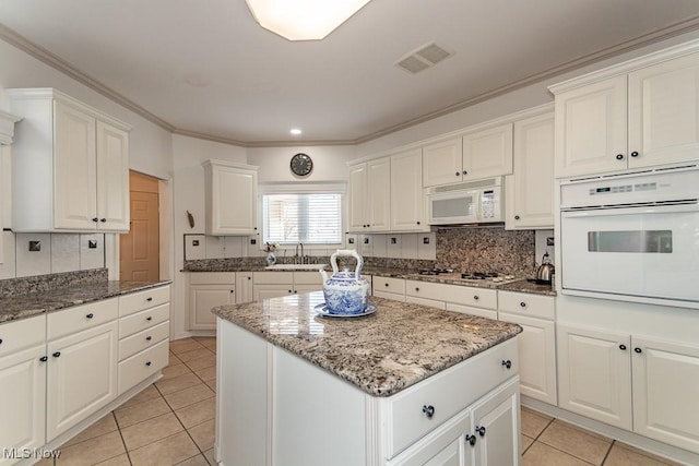 kitchen featuring decorative backsplash, white appliances, light tile patterned flooring, and visible vents