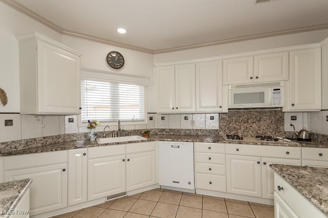 kitchen with backsplash, white appliances, white cabinets, and a sink