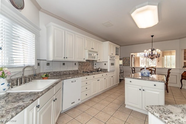 kitchen featuring white appliances, light tile patterned floors, a sink, crown molding, and a chandelier