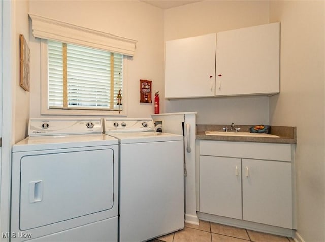 laundry area featuring light tile patterned floors, a sink, cabinet space, and separate washer and dryer