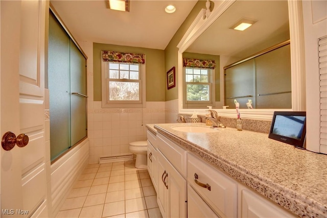 bathroom featuring vanity, a baseboard heating unit, tile patterned floors, toilet, and tile walls