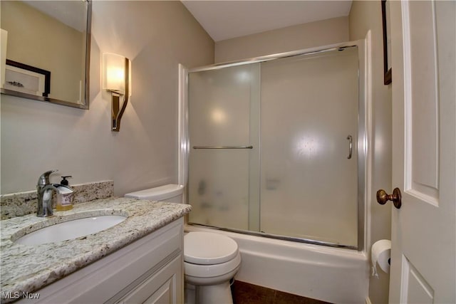 bathroom with combined bath / shower with glass door, toilet, and vanity