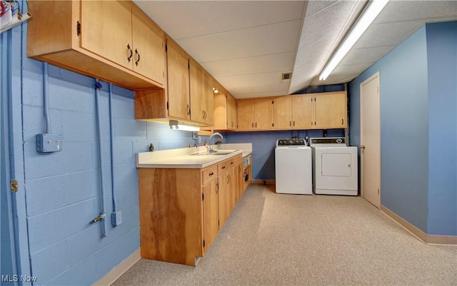 washroom with a sink, cabinet space, baseboards, and washer and clothes dryer