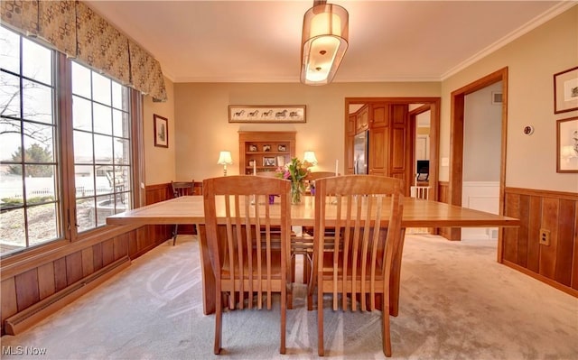 dining room featuring light colored carpet, a healthy amount of sunlight, and wainscoting