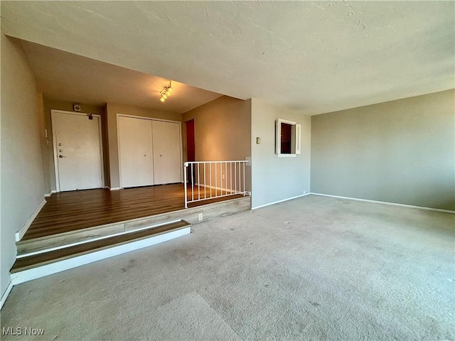 unfurnished room featuring carpet flooring, baseboards, and a textured ceiling