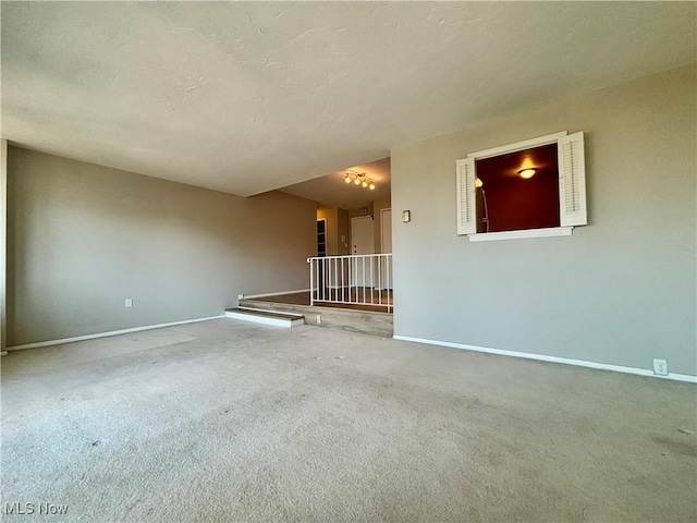 carpeted spare room with baseboards and a textured ceiling