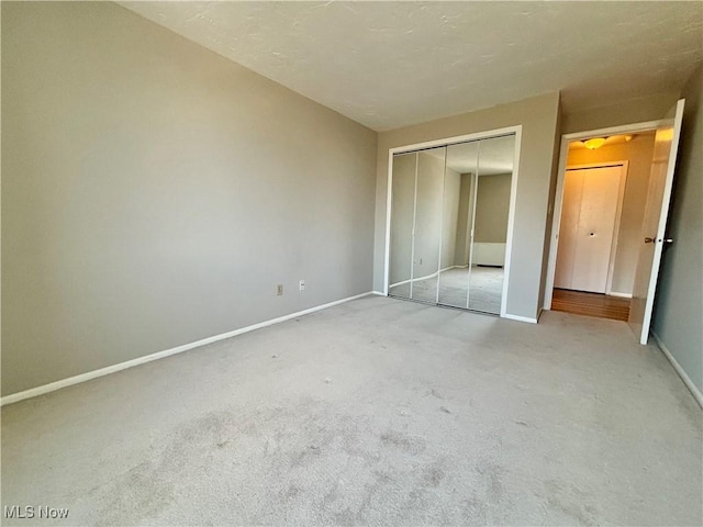 unfurnished bedroom featuring a closet, baseboards, and light colored carpet