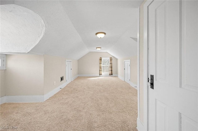 bonus room featuring visible vents, baseboards, carpet, vaulted ceiling, and a textured ceiling