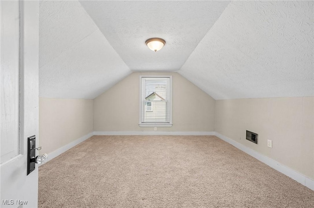 bonus room featuring lofted ceiling, carpet, baseboards, and a textured ceiling