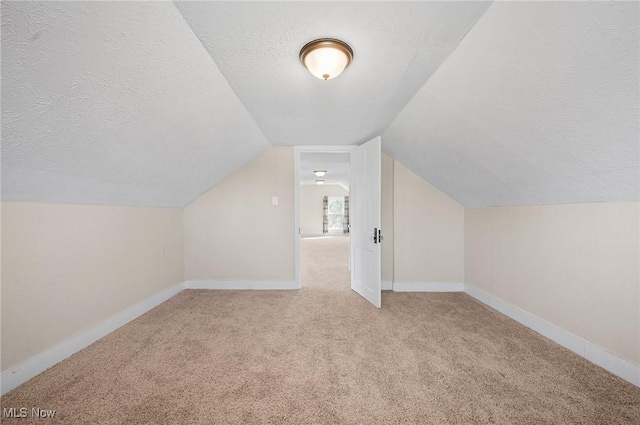 bonus room featuring a textured ceiling, lofted ceiling, baseboards, and carpet floors