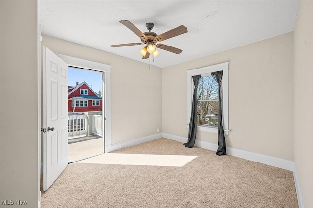 carpeted empty room featuring a ceiling fan and baseboards