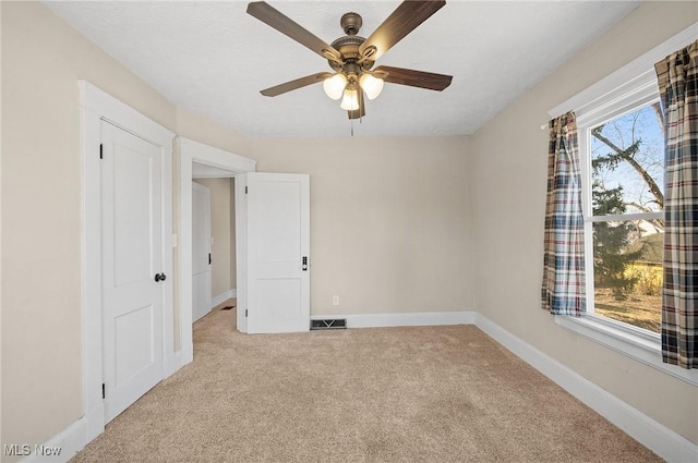 unfurnished room featuring baseboards, carpet floors, visible vents, and ceiling fan