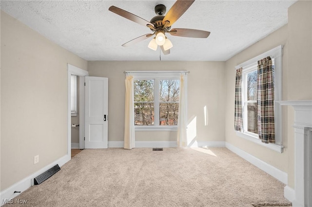 carpeted empty room with baseboards, visible vents, a textured ceiling, and a ceiling fan