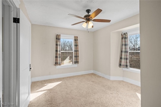 empty room with a ceiling fan, a healthy amount of sunlight, baseboards, and carpet floors