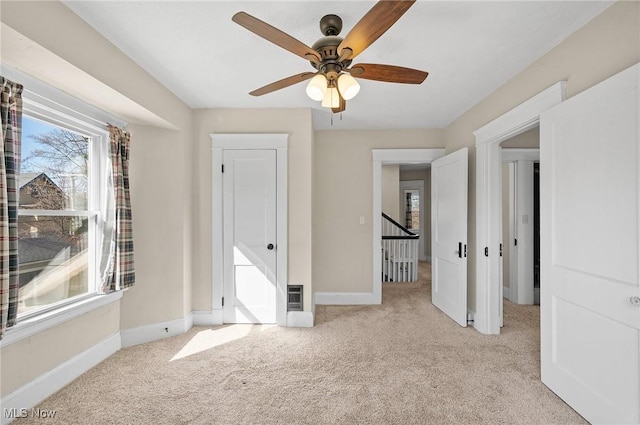 unfurnished bedroom featuring baseboards, light carpet, and ceiling fan