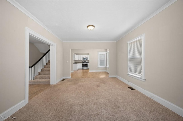 unfurnished living room with visible vents, light colored carpet, baseboards, and ornamental molding