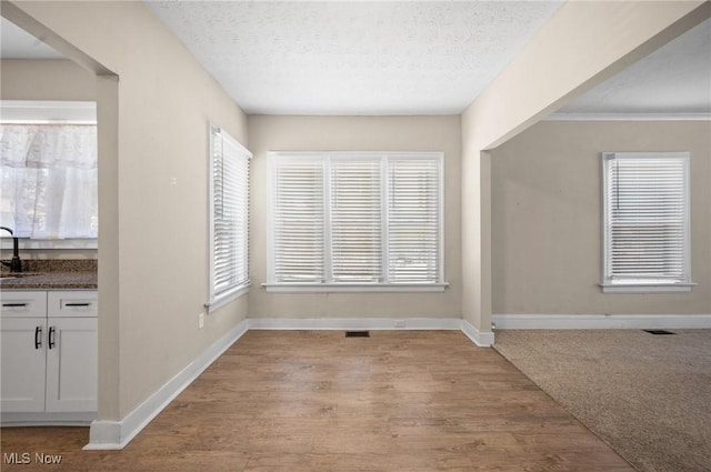 unfurnished room with visible vents, baseboards, a textured ceiling, and wood finished floors