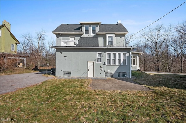 view of front of property featuring stucco siding, a balcony, and a front yard