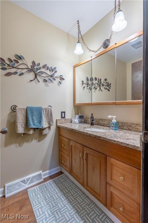 bathroom featuring visible vents, baseboards, wood finished floors, and vanity