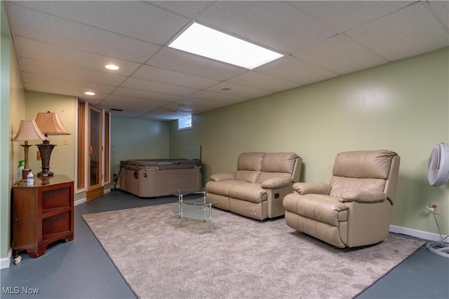 living area with a drop ceiling, recessed lighting, concrete floors, and baseboards