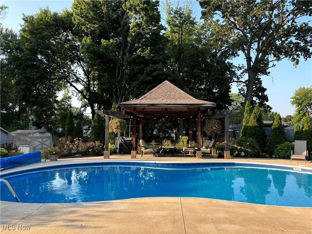 view of pool featuring a covered pool, a gazebo, a storage unit, an outdoor structure, and a pergola