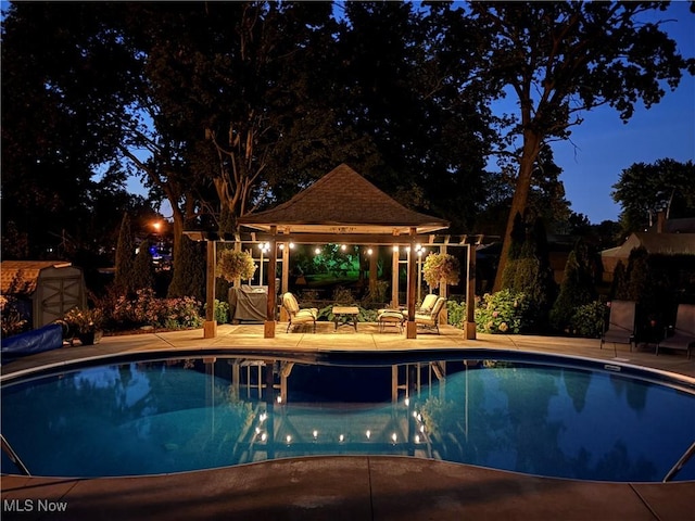 pool at twilight featuring a gazebo, an outdoor pool, and a patio