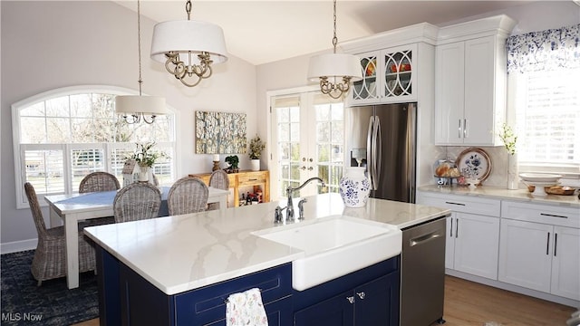 kitchen with blue cabinetry, pendant lighting, appliances with stainless steel finishes, white cabinets, and a sink