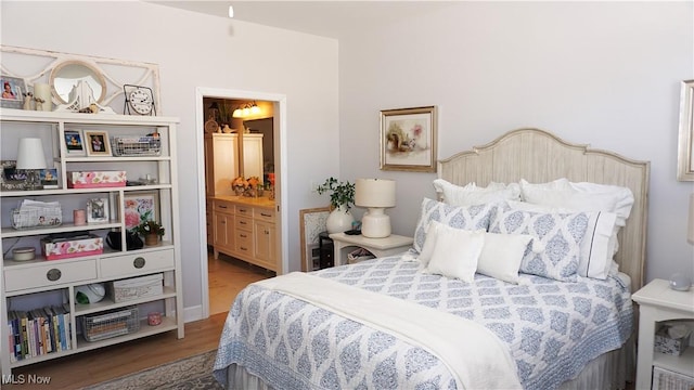 bedroom with ensuite bath and wood finished floors