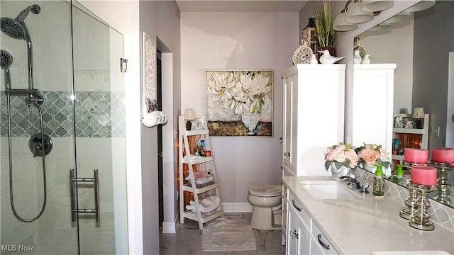 bathroom with vanity, a shower stall, toilet, and baseboards